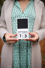 Woman holds calendar with the date september 13 outdoors.
