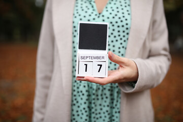 Woman holds calendar with the date september 17 outdoors.