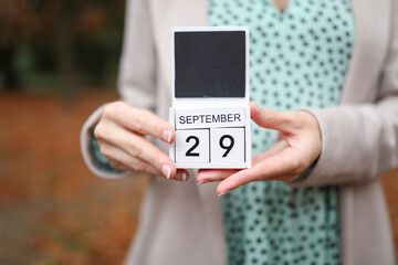 Woman holds calendar with the date september 29 outdoors.