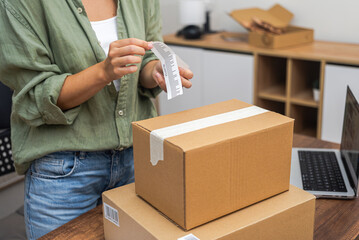 A woman customer labels a cardboard parcel with a barcode for a swift online shopping refund. 