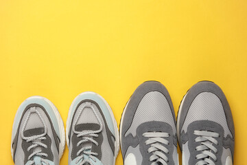 Male and female pair of sports shoes for running on a yellow background