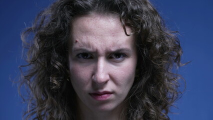 Displeased stern woman sighing deeply feeling bored and annoyance while looking at camera on a blue...