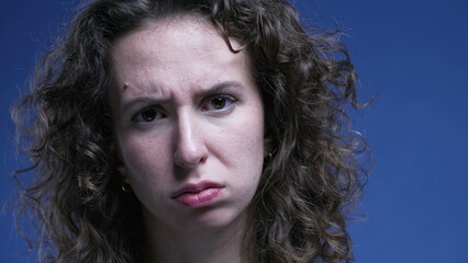 Displeased stern woman sighing deeply feeling bored and annoyance while looking at camera on a blue background - obrazy, fototapety, plakaty