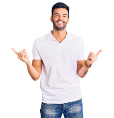 Young handsome hispanic man wearing casual clothes smiling confident pointing with fingers to...