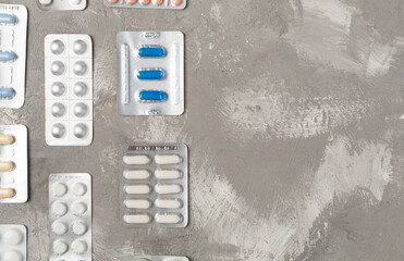 Pills in blister packaging on concrete background, top view