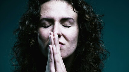 Faithful woman opening eyes to sky in PRAYER. Close-up face 20s person having HOPE during difficult times