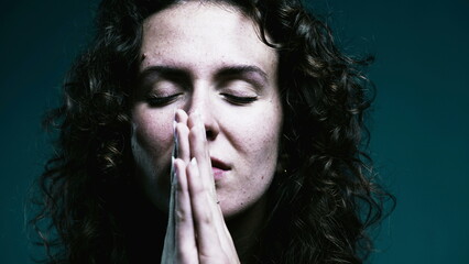 Faithful woman opening eyes to sky in PRAYER. Close-up face 20s person having HOPE during difficult...