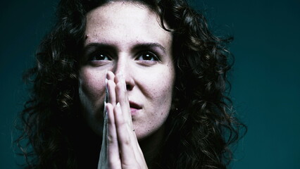 Faithful woman opening eyes to sky in PRAYER. Close-up face 20s person having HOPE during difficult times