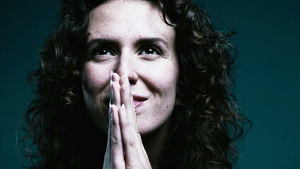 Faithful woman opening eyes to sky in PRAYER. Close-up face 20s person having HOPE during difficult times