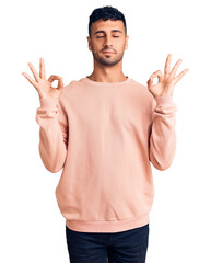 Young hispanic man wearing casual clothes relaxed and smiling with eyes closed doing meditation gesture with fingers. yoga concept.