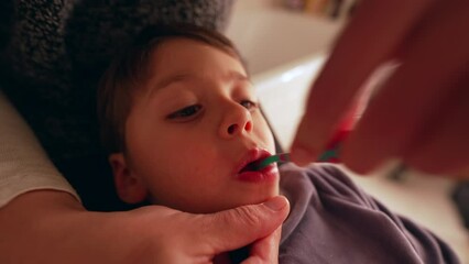 Closeup child's face while mother brushes teeth, dental hygiene night routine before bed, young boy's mouth during dental hygiene