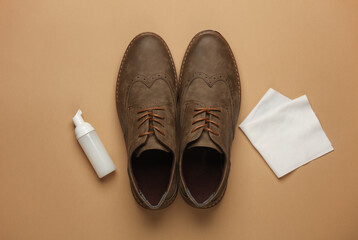 Brogue shoes with cleaning foam and rag on beige background. Shoe care