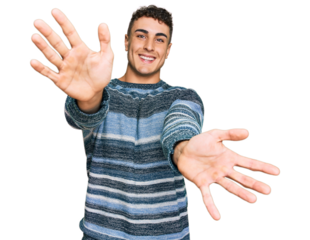 Hispanic young man wearing casual clothes looking at the camera smiling with open arms for hug. cheerful expression embracing happiness.