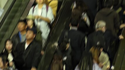TOKYO, JAPAN - NOV 2023 : Crowd of people on the escalator at night. Shot in busy rush hour. Japanese people, tourists, diversity and lifestyle concept video. Blurred time lapse shot.