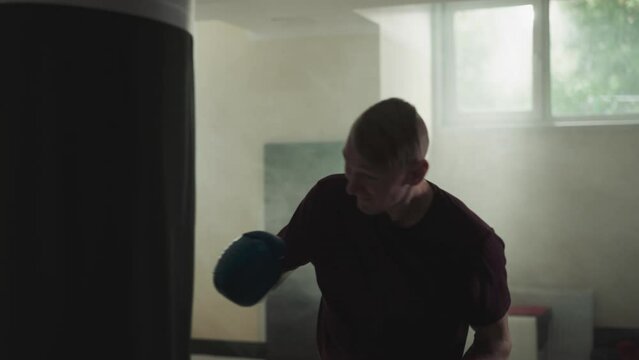 Sportsman exercises beating punching bag in gym