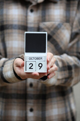 Woman in warm shirt holds calendar with date October 29