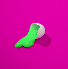 Creative layout with pink slime in broken chicken egg shell. Bright pink background with shadow. Visual trend. Halloween, food conceppt. Minimalistic aesthetic still life. Fresh idea