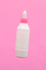 Glue bottle on pink background. Minimalist photo. Top view