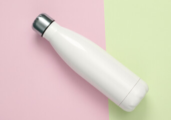 White metal thermal bottle for water on a pastel background. Stainless Steel Vacuum Insulated...
