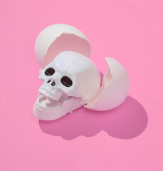 Creative layout with skull and eggshell. Bright pink background with shadow. Visual halloween trend. Minimalistic aesthetic still life. Fresh idea
