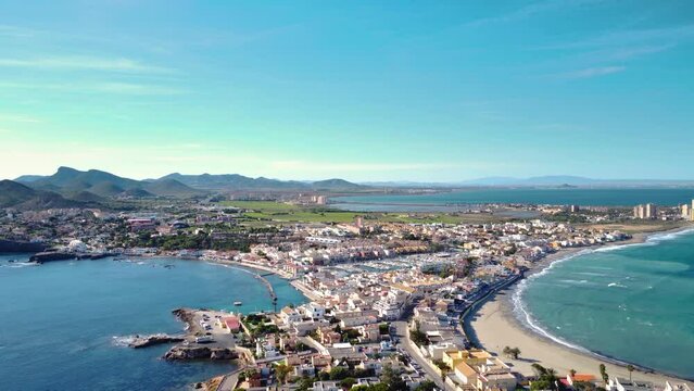 Aerial drone perspective of famous region La Manga, Murcia Province. Spain. "Cabo de Palos" - Cape Palos. Seaside sandspit of Mar Menor in the Region of Murcia. Drone forward above the village. Travel