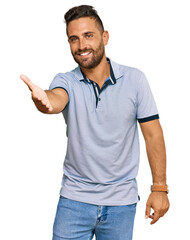 Handsome man with beard wearing casual clothes smiling friendly offering handshake as greeting and welcoming. successful business.