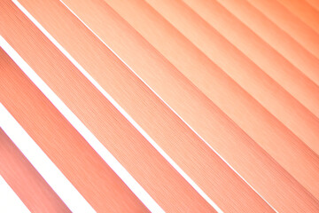 Background of vertical orange blinds curtains. Pleated roller blinds. Orange striped background.