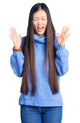 Young beautiful chinese woman wearing casual turtleneck sweater celebrating mad and crazy for...