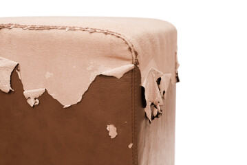 An ottoman on a white background, the leather upholstery is peeling off the pouf, cats and children have torn the upholstery of soft furniture