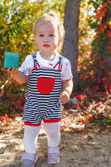 Cute child girl baby toddler In a striped jumpsuit walks outdoors in summer 