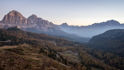 View on beautiful alpine valley during autumn sunrise with fog and golden larches, Dolomites, Italy
