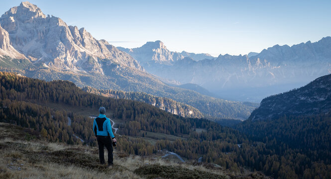 Man with camera enjoying views on beautiful mountain valley during early morning, Dolomites, Italy