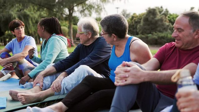 Senior, multiracial people having fun after yoga sport class in the nature at public park. Healthy life style and elderly community