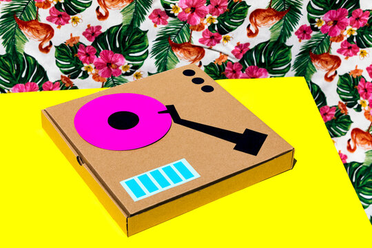 Antique turntable made with cardboard box on yellow table over floral background