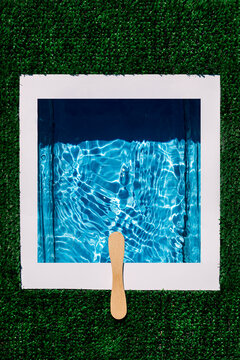 Overhead shot of diving platform made with wooden stick over rippled water in swimming pool isolated on green artificial background