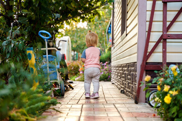 Child baby walks along a path on a summer cottage house
