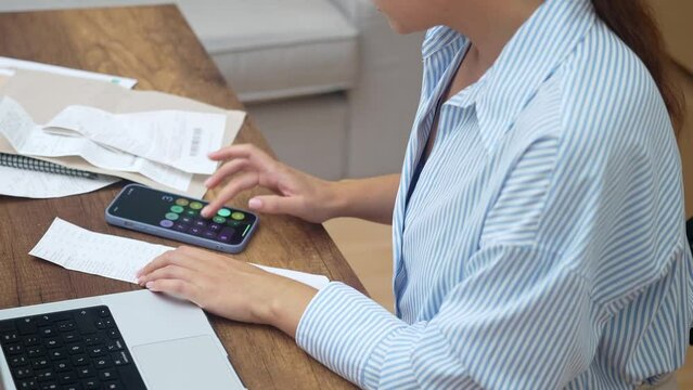 Home finance: A woman tackles bills and online payments on her laptop. Crunching numbers, managing accounts, and reviewing loan rates