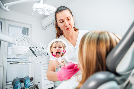 Little girl looking at mirror while dentist doctor doing teeth prevention with excavator and mirror medical tools. in stomatology clinic. Healthcare, kid's health and medicare industry concept image.