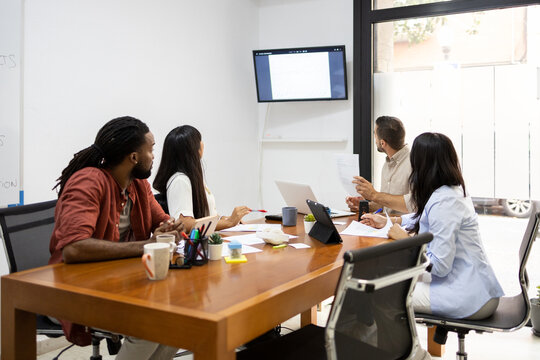 Multiracial colleagues discussing over monitor in office