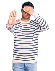 Hispanic handsome young man wearing casual clothes and glasses covering eyes with hands and doing stop gesture with sad and fear expression. embarrassed and negative concept.