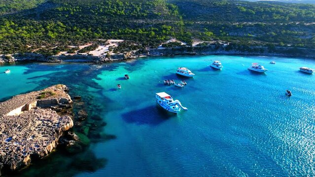 Aerial Panning Shot Of White Nautical Vessels Moored On Wavy Sea By Mountains During Sunny Day - Paphos, Cyprus