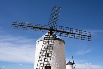 Low angle view of ancient wind mill with wood blades in of Region of Castilla la Mancha, Spain over blue sky