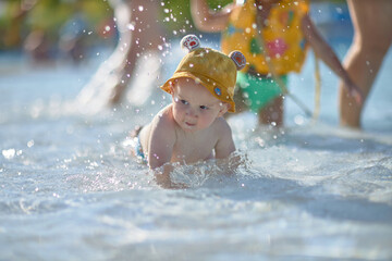 a little half a year old, a baby baby crawling on the water, smiling, outdoors, in a panama hat, in...