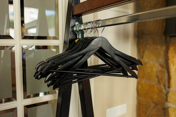 Black wooden clothes hangers without clothes on metal rack at the entrance to the restaurant. Hallway of a hotel or store. Wardrobe corner, loft style .