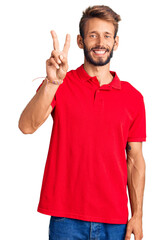 Handsome blond man with beard wearing casual clothes showing and pointing up with fingers number two while smiling confident and happy.