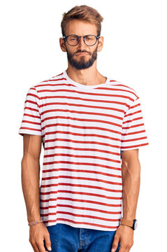 Handsome blond man with beard wearing casual clothes and glasses depressed and worry for distress, crying angry and afraid. sad expression.