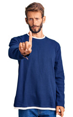 Handsome blond man with beard wearing casual sweater pointing with finger up and angry expression, showing no gesture