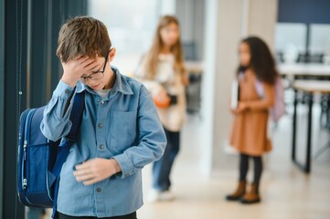 School friends bullying a sad boy in corridor at school