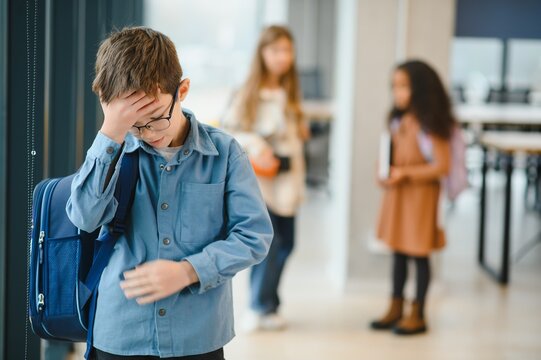 School friends bullying a sad boy in corridor at school - Powered by Adobe