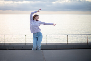 Young woman dancing in front of the sea at sunrise.